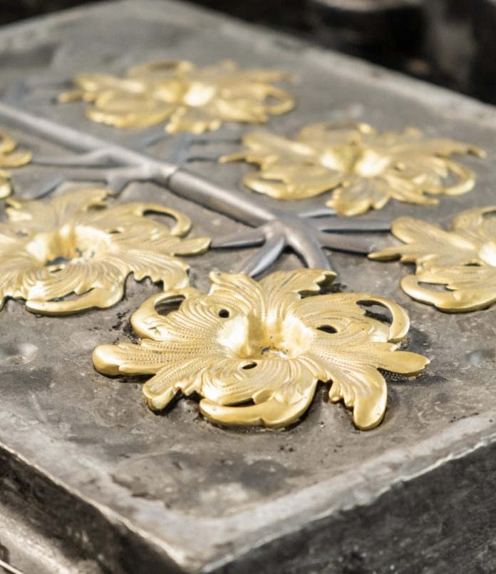 Stylish golden flower and grey branches molded in high precision cast in traditional production plant workshop extreme close view