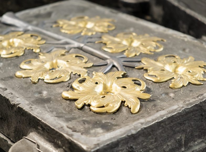 Stylish golden flower and grey branches molded in high precision cast in traditional production plant workshop extreme close view